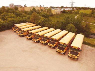 Okul otobüsleri eğitim sezonu için hazır. Bir sürü okul otobüsü park ediyor. Sarı rayları ve akşam gökyüzü olan, genç üniversite öğrencilerini alıp bırakmaya hazır insansız hava aracı parkı. Okul konseptine dönelim..