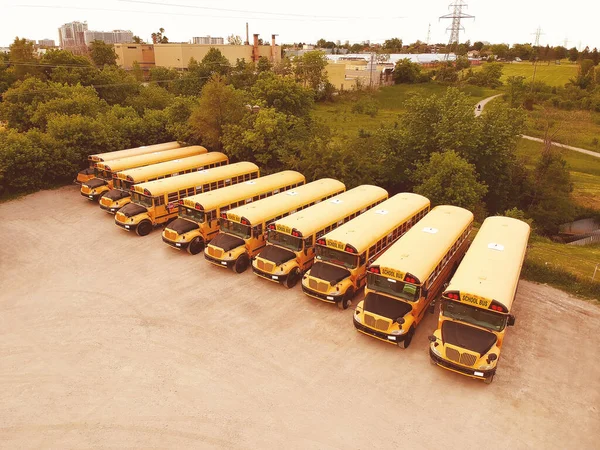 School bus vehicles ready for school educational season. Parking lot of school busses. Drone aerial view of parking yard with yellow tracks and evening sky ready to pick up and drop off young college students. Back to school concept.
