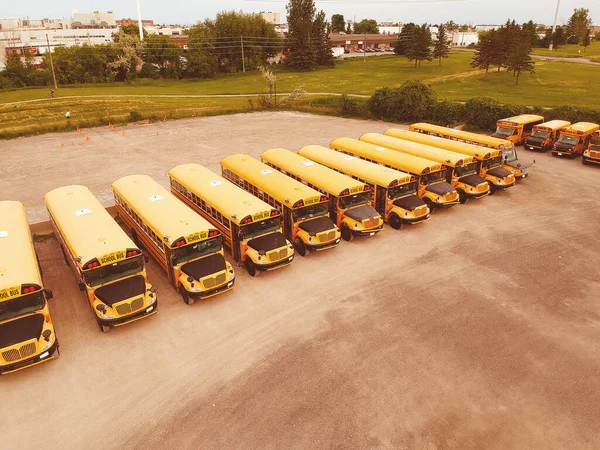 Skolbussarna klara för skolsäsongen. Parkeringen av skolbussar. Drone antenn utsikt över parkeringsplatsen med gula spår och kväll himlen redo att plocka upp och släppa av unga college studenter. Tillbaka till skolkonceptet. — Stockfoto