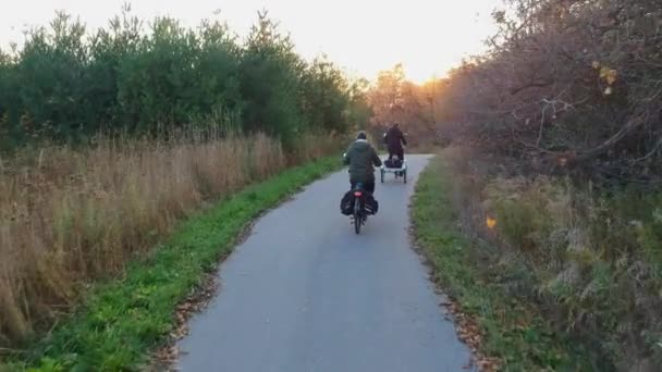 Ταξιδιώτες, γυναίκες και άνδρες ποδηλασία στα ποδήλατα ή ιππασία ποδήλατα το φθινόπωρο ή το φθινόπωρο αγροτικό πάρκο σε χρυσή ώρα ηλιοβασίλεμα. Δραστηριότητα διακοπών, εναέρια άποψη από ψηλά πάνω από πορτοκαλιές, κίτρινα και πράσινα δέντρα. — Αρχείο Βίντεο