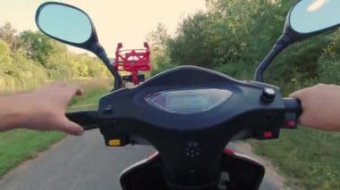 Şehir parkının yeşil alanından mobiletle geçerek. Asfalt yol ve gün batımı. Akşam eğlencesi eğlencesi. Çevreye duyarlı ekolojik güç nakli. Etkin yaşam biçimi.