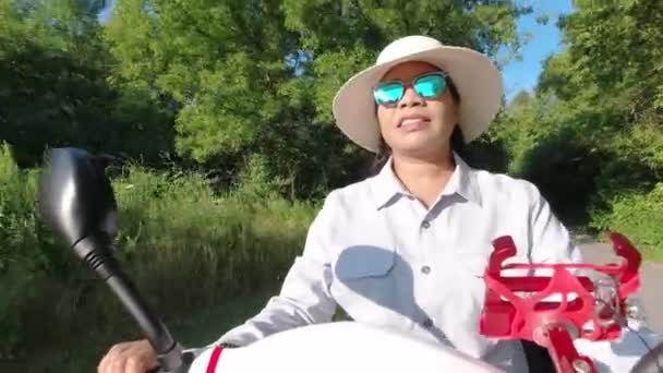 Donna afroamericana in occhiali da sole e cappello guida scooter elettrico di mobilità. Libertà di guida veicolo personale lungo il parco verde della città in estate tramonto. — Video Stock