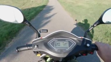 Şehir parkının yeşil bölgesinde scooter sürüyorum. Asfalt yol ve güneş. Eğlence amaçlı eğlence için. Çevreye duyarlı ekolojik güç nakli. Etkin yaşam biçimi.