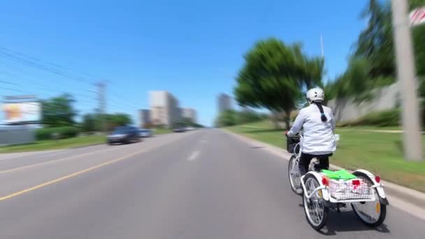 自転車や電気自転車に乗って、後ろから撮影し、生態学の概念。ペダリング支援で電子トリックを運転する女性。代替モータパワー輸送. — ストック動画