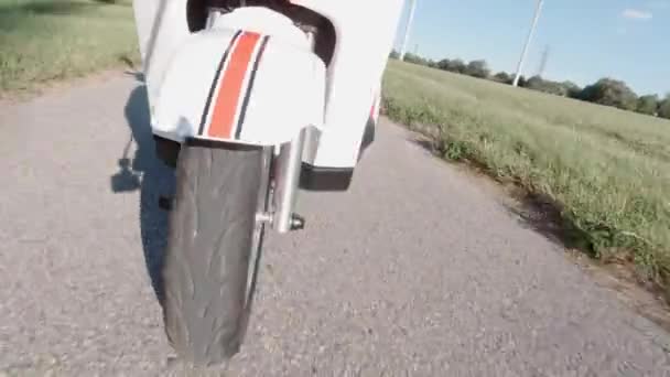 Primo piano di una ruota anteriore che gira sotto il cofano mentre guida scooter elettrico. Vista da un lato. Trasporto alternativo moderno, opzione di mobilità popolare. — Video Stock