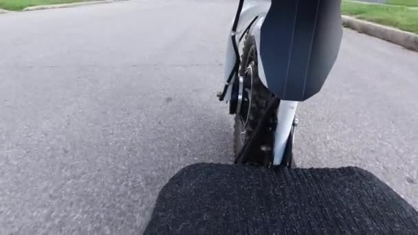 Sluiten van een voorste motorwiel draaien onder de motorkap tijdens het rijden elektrische scooter. Uitzicht vanaf de zijkant. Modern alternatief vervoer, populaire mobiliteit optie. — Stockvideo
