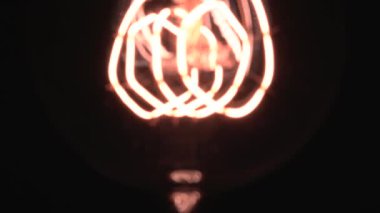 Edison ampulü yavaş yavaş odak ve detaylarla ortaya çıkar. Vintage filament ampulün altında kayarak alttaki makro görüntüyü bokeh efektiyle parlıyor ve parlatıyor. 4K.
