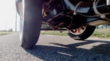 Elektronik bisiklet ya da elektrikli scooter, aşağıdan çekilmiş, ekoloji konsepti. E scooter parkın yeşil bölgesinden geçiyor. Bir motorun aküsünü kapat.