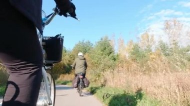 Parkın yeşil bölgesinde elektrikli bisiklet süren bir bisikletçi. Ekoloji konsepti. Arkadan vurulmuş..