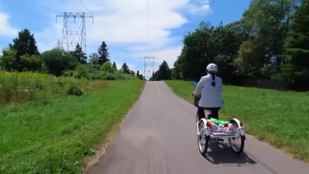 E-Bike oder Elektrofahrrad fahren, von hinten angeschossen, ökologisches Konzept. Frau am Steuer eines elektronischen Trikes mit Tretunterstützung. Alternative Antriebe. — Stockvideo