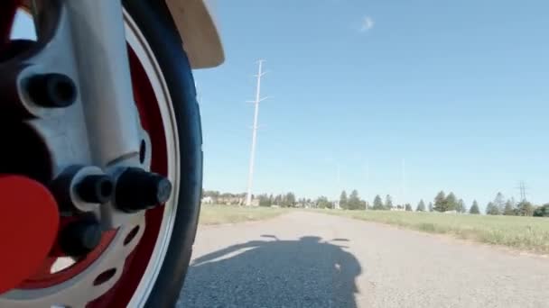 Primo piano di una ruota anteriore che gira sotto il cofano mentre guida scooter elettrico. Vista dall'alto. Trasporto alternativo moderno, opzione di mobilità popolare. — Video Stock