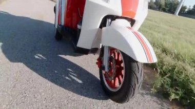 Motorlu scooter kullanırken kaputun altında dönen ön tekerleği kapat. Yandan bak. Modern alternatif ulaşım, popüler hareketlilik seçeneği.