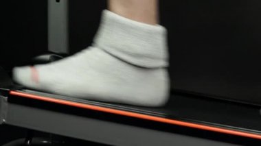 Koşu bandıyla ağırlık terapisi sırasında orta yaşlı insan ayakları. Spor salonundaki adamdan çalış. Kilo verdikten sonra spor salonunda yürüyüş yeteneklerini geliştirmeye çalışan biri. Sağlıklı vücut için egzersiz..