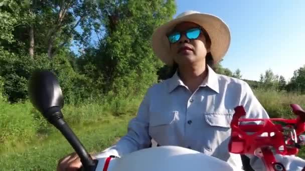 Donna afroamericana in occhiali da sole e cappello guida scooter elettrico di mobilità. Libertà di guida veicolo personale lungo il parco verde della città in estate tramonto. — Video Stock