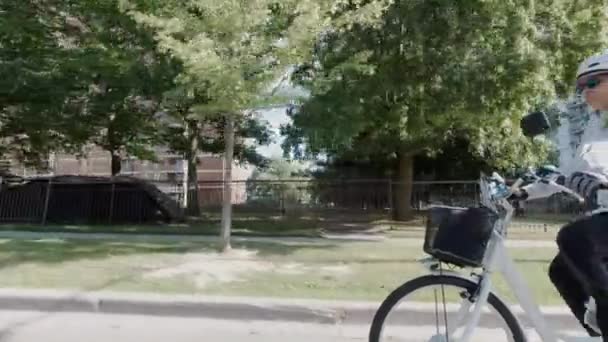 Langzame beweging van de vrouw in de helm paardrijden elektrische fiets in de stad op zomerdag. Natuurlijke verlichting. Zicht op de accu en motor van de zijkant. Zomer vrijetijdsbesteding. — Stockvideo