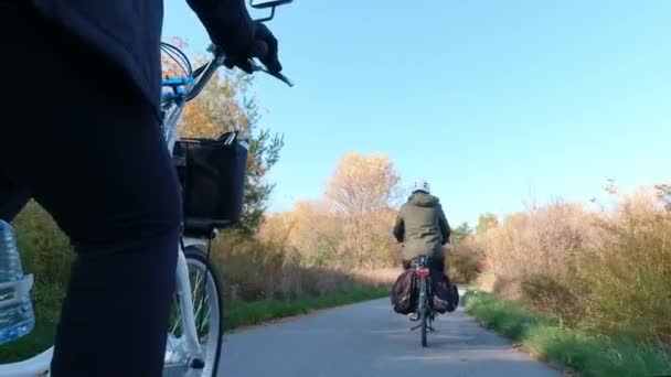 Pareja de viajeros montados en bicicleta eléctrica, E-bike o bicicletas al atardecer en el parque forestal. Naturaleza otoñal relámpago natural. Turismo activo, paseos en naranja deja parque en América del Norte . — Vídeos de Stock