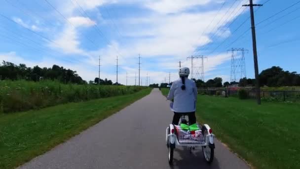 Radfahrer mit einem Elektrofahrrad auf der Grünfläche des Parks. Ökologiekonzept. Schuss von hinten. — Stockvideo