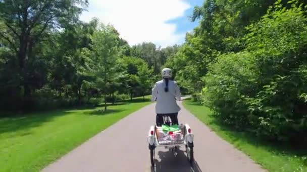 E-Bike oder Elektrofahrrad fahren, von hinten angeschossen, ökologisches Konzept. Frau am Steuer eines elektronischen Trikes mit Tretunterstützung. Alternative Antriebe. — Stockvideo