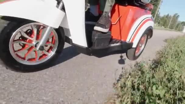 Gros plan d'une roue avant tournant sous le capot tout en conduisant un scooter électrique. Vue de côté. Transport alternatif moderne, option de mobilité populaire. — Video