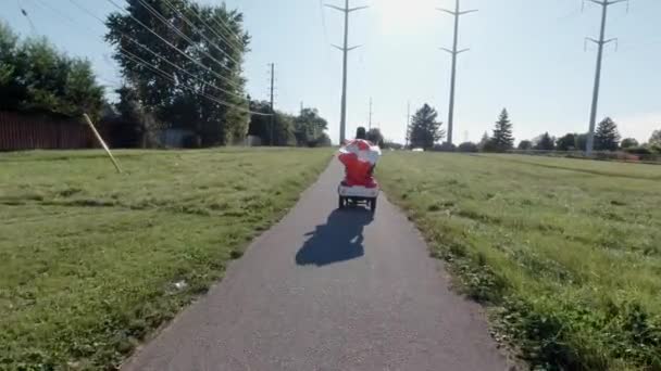 Donne che cavalcano uno scooter elettrico nel parco della città, tenendo la bandiera canadese al vento. Felice cittadino canadese guida ecologico trasporto di energia consapevole. Stile di vita adulto attivo. — Video Stock