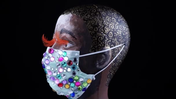 Maniquí de cara de mujer afroamericana pintada que usa una mascarilla médica de piedras preciosas de lujo de moda para protegerse de virus y polvo, girando lentamente. Concepto de máscara urbana prevención de gérmenes. — Vídeos de Stock