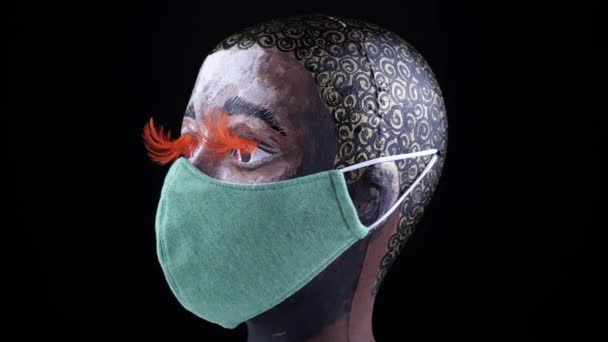 Cabeza de mujer afroamericana con máscara quirúrgica o médica, girando y mirando a la cámara. Concepto de brote de patógenos por Coronavirus. Bacterias y enfermedades virales 2019-nCoV protección y prevención. 4k. — Vídeo de stock
