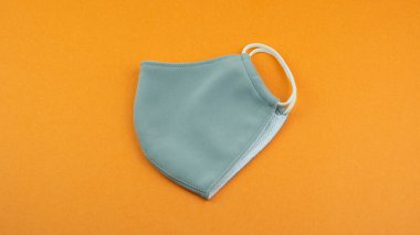 Virüsten korunmak için yeniden kullanılabilir toz maskesi ve banliyö sakinleri için kirlilik. PPE kişisel koruyucu ekipmanlar küresel salgın Covid 19 koronavirüs, kirlilik nedeniyle zorunludur. Turuncu arkaplan.