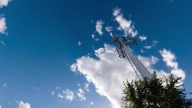 Cep telefonu iletişim antenleri, 3G, 4G, 5G. Yazın bulutlu mavi gökyüzünü hızla hareket ettiren antenin zaman akışı. Vericili hücresel GSM kulesi. Telekomünikasyon baz istasyonu ağı.