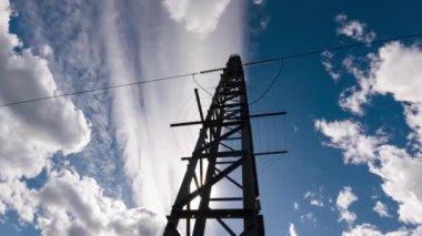 Endüstriyel yeşil enerji şebekesinin hızlandırılmış elektrik şebekesi üzerinde mavi bulutlar olan verici silueti. Yüksek voltajlı güç hattı ile günbatımı arkaplanı zamanlaması.