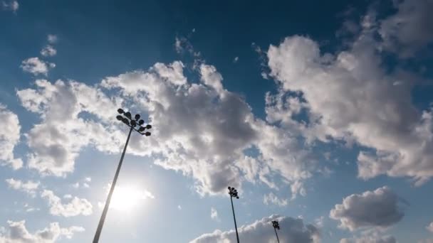 Timelapse com torres leves de um estádio de futebol contra um pôr-do-sol e nuvens de verão, movimento rápido e liso cinematográfico do céu. Lanternas de estádio de futebol e lapso de tempo à noite. — Vídeo de Stock