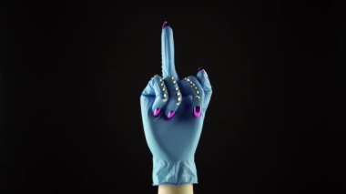 Woman wrist hand and middle finger or fuck you symbol. Hand in the blue medical decorated glove PPE. Female palm in disposable surgical protective glove. Concept victory fight of COVID 19 coronavirus