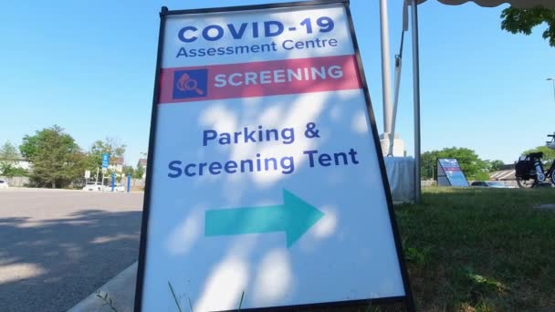 Covid-19 Assessment Centre Screening Parking and Screening Tent Schild in der Nähe des Krankenhauses in der Stadt. Coronavirus-Test für Arbeitnehmer wegen Pandemie. Der Kampf mit dem Virus und der Kontrolle der zweiten Welle. — Stockvideo