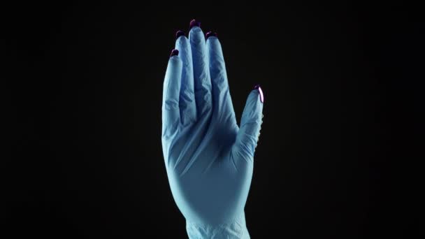 Main de poignet de femme dans le bleu médical décoré PPE gant sur fond noir. Paume féminine en gant de protection chirurgicale jetable. Concept des doublures frontales pandémiques COVID 19 coronavirus et de l'infirmière. — Video