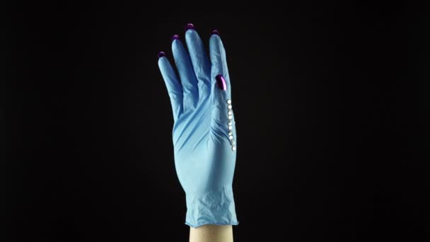 Mão de pulso de mulher na luva decorada médica azul EPI em fundo preto. Palma feminina em luva protetora cirúrgica descartável. Conceito de COVID 19 coronavírus pandemia forros dianteiros e enfermeira. — Vídeo de Stock