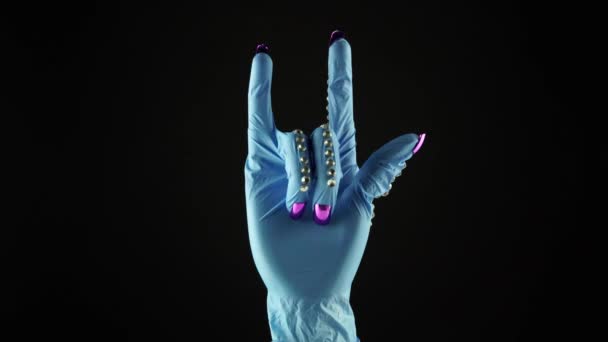 Mão de pulso de mulher e símbolo de rocha. Mão na luva decorada médica azul EPI. Palma feminina em luva protetora cirúrgica descartável. Conceito de rocha e luta de vitória do COVID 19 coronavírus. — Vídeo de Stock