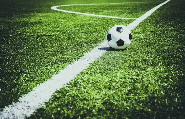 Yeşil saha üzerindeki beyaz köşe işaretleri tarafından çerçeveli bir futbol topu. Spor arka plan.