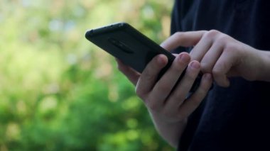 Küçük el smartphone elinde tutan çocuğun yakın çekim. Bilgisayar oyunları oynarken veya Internet açık havada yaz güneşli günde tarama çocuk. Modern elektronik becerikli alet için bağımlısı anonim küçük çocuk. 6 k video ile downscale.