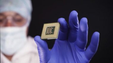 CPU bir teknisyen elinde. İşlemci için belirgin kusurları muayene ediliyor. Siyah arka plan üzerine izole atış.