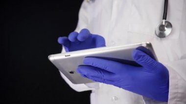Bir tablet ile çalışan genç doktor eller Close-up. Ağır çekimde. Siyah arka plan üzerine izole atış.