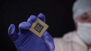 Ultra Modern elektronik üretim fabrika tasarımında steril Coverall tutan mikro yongasında eldiven ve Examines ile BT mühendisi. Siyah arka plan üzerine izole atış.