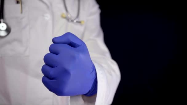 クローズ アップ成功治療後親指で行うブルー ラテックス手袋の医師 黒の背景に分離されたショット — ストック動画