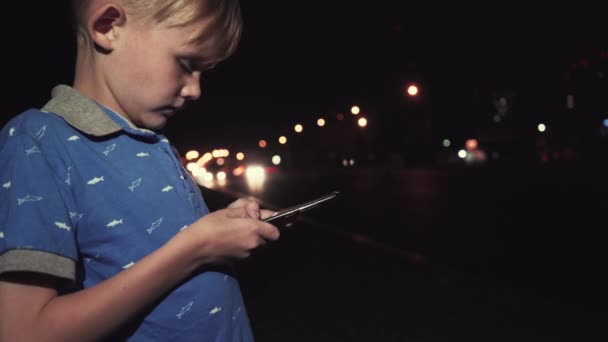 Kleine Jongen Spelen Van Mobiele Telefoon Stad Bij Nacht — Stockvideo