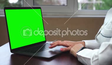 Yakın çekim yeşil ekran ile bir dizüstü bilgisayar üzerinde çalışan bir doktor bir kadeh. Bilim adamı ile chroma anahtar yeşil ekran laptop kullanıyor