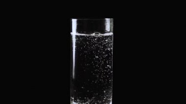 Mo kabarcıklar mineral su, yavaş bir siyah arka plan üzerine bir bardak soda