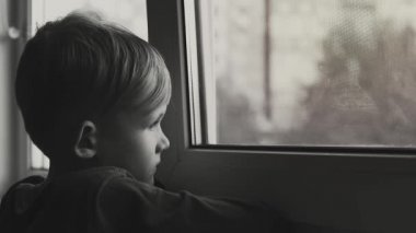 çocuk üzgün ve yalnız pencereden bakıyor. Çocuk depresyonda siyah beyaz vurulur