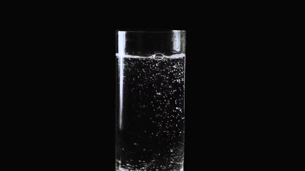 Ralentissez. Bulles d'eau minérale, soude dans un verre sur fond noir 