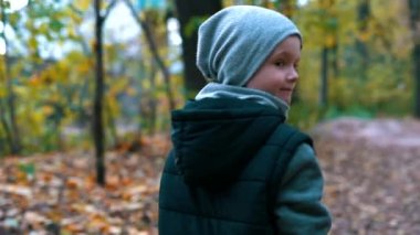 Bir çocuk sonbahar Ormanda yürür.
