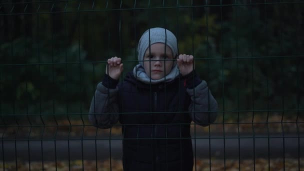 Одинокий Несчастный Несчастный Мальчик Позади Цепляющийся Забор — стоковое видео