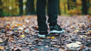 Bir çocuk parkı sonbaharda sarı yapraklarda ayak yakın çekim. Sarı düşen yapraklar ormandaki bir çocuk geçer.