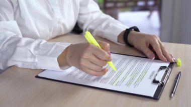 Masa altı çizili sözcükleri sözleşmesindeki fold ofiste oturan kadın. İçinde belgelerde yeşil işareti önemli şeylerle vurgulayarak iş kadını.